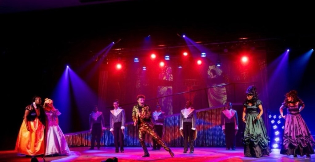Prince Charming dances with men in long coats and Snow White and Cinderella looking on