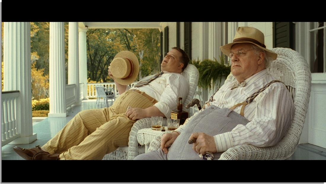 An older man and his son having a conversation on a porch