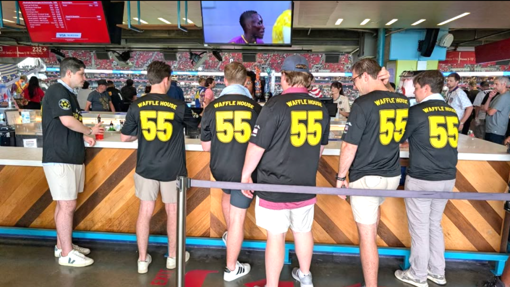 Seven men in Waffle House soccer jerseys at a bar in Atlanta Stadium