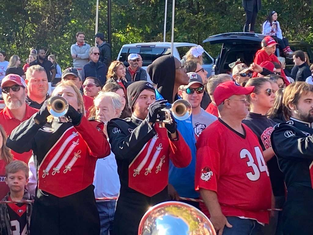 Trumpet players surrounded by people lined up on a street