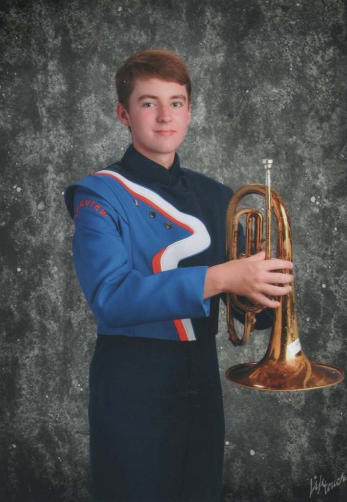 A young man in marching band uniform holding a mellophone