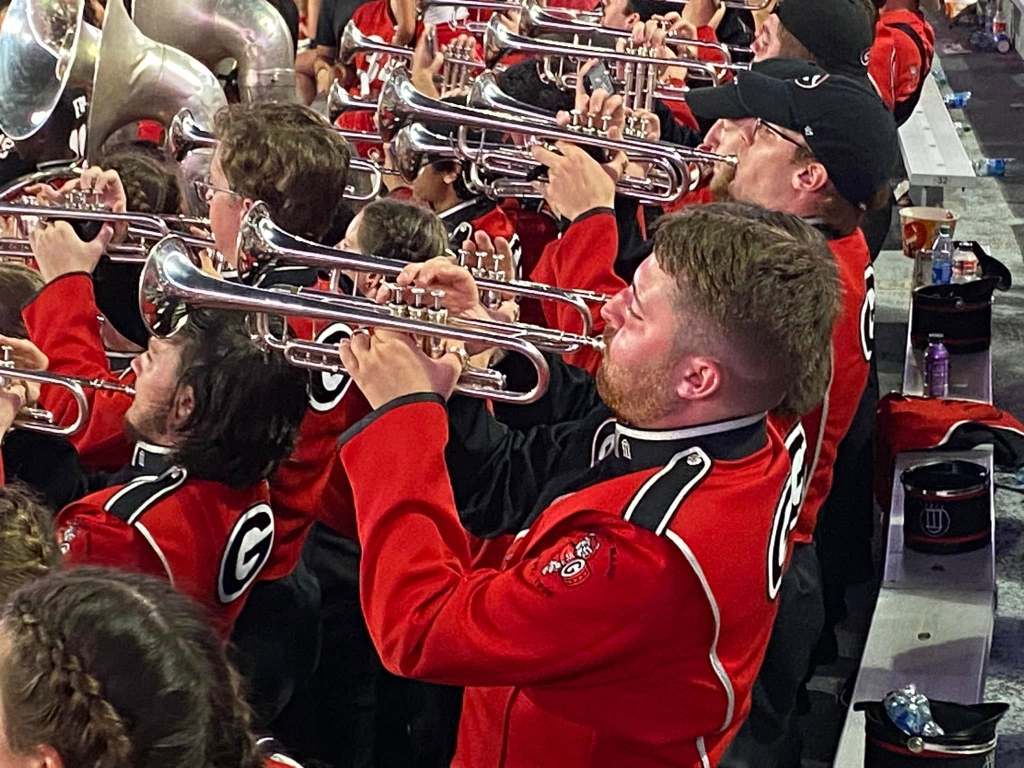 College band members play trumpets in the stands