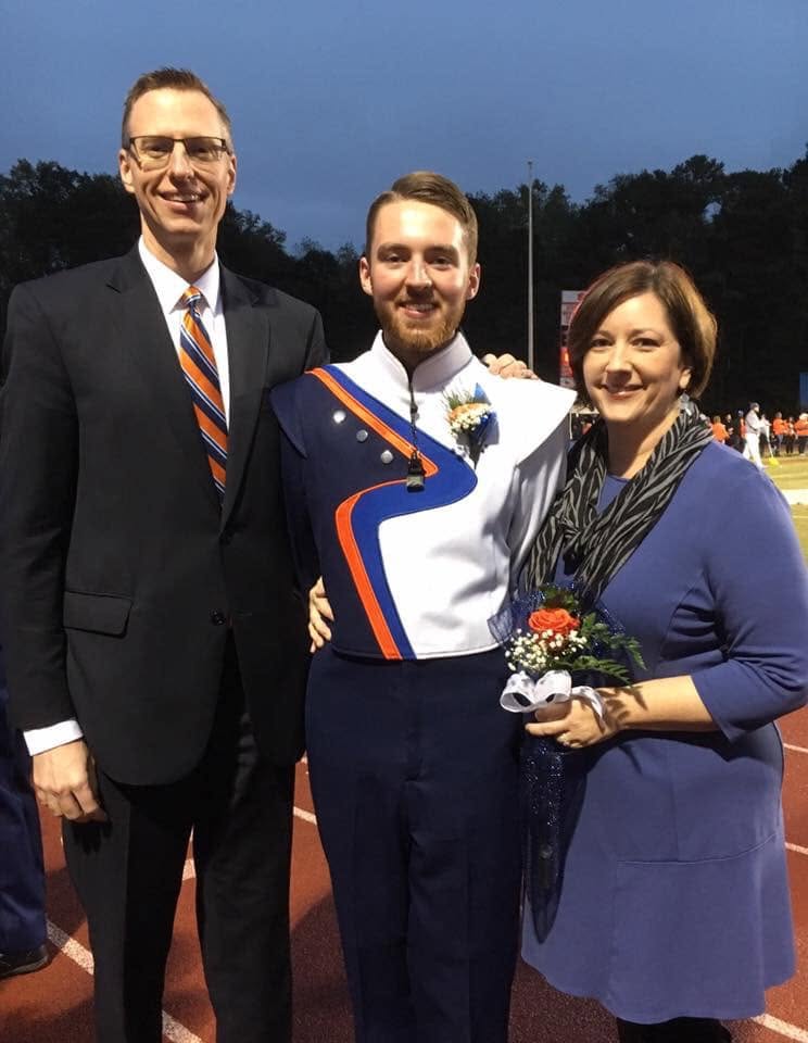 Man and woman with young man in marching band uniform