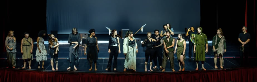 A group of costumed actors on stage at the end of a show.