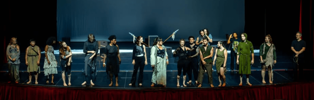A group of costumed actors on stage at the end of a show.