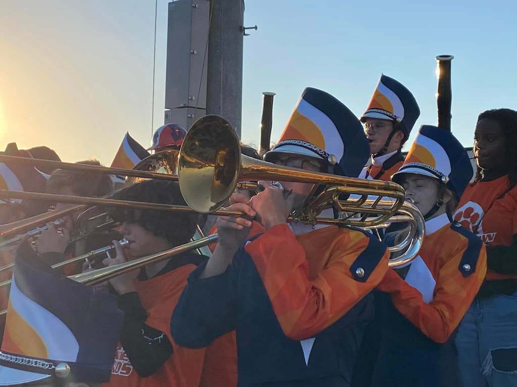 High school marching band playing in the stands with the sunset in the background