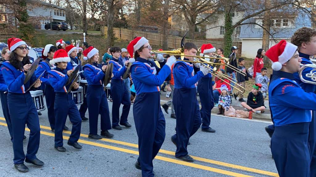 Marching band playing their instruments wearing Santa hats