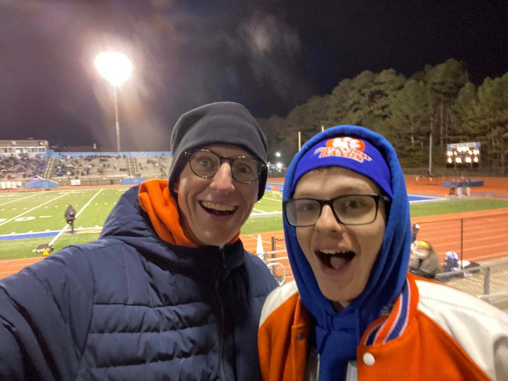 Father and son in winter coats at a football stadium