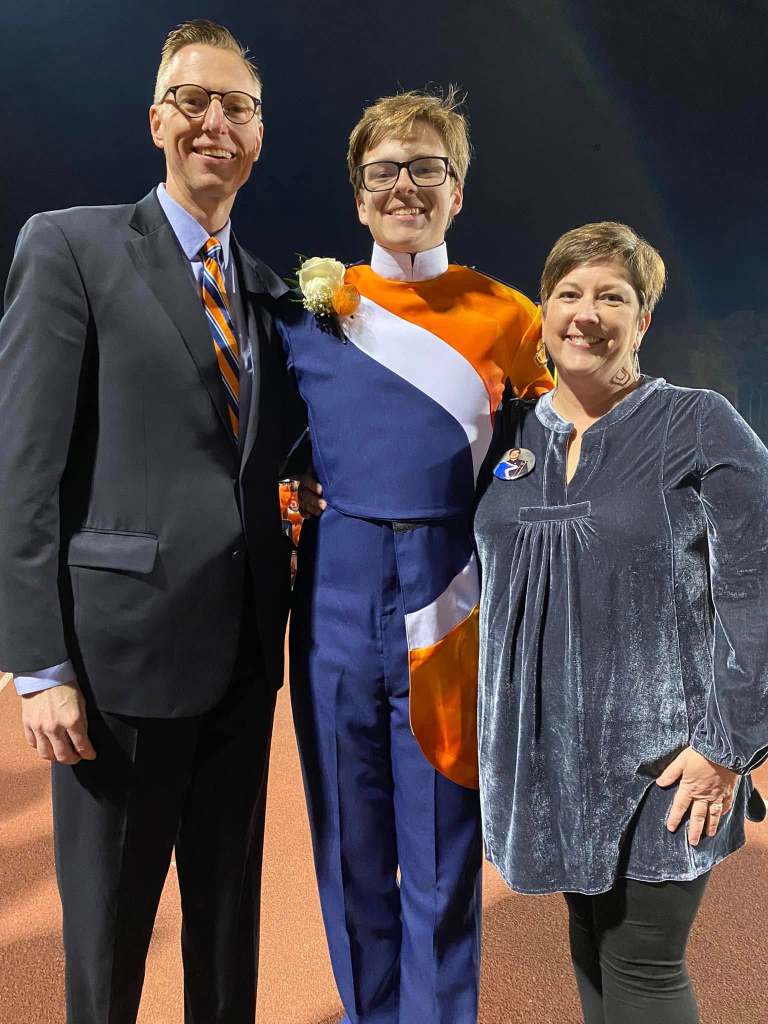 Parents with a young man in high school marching band uniform