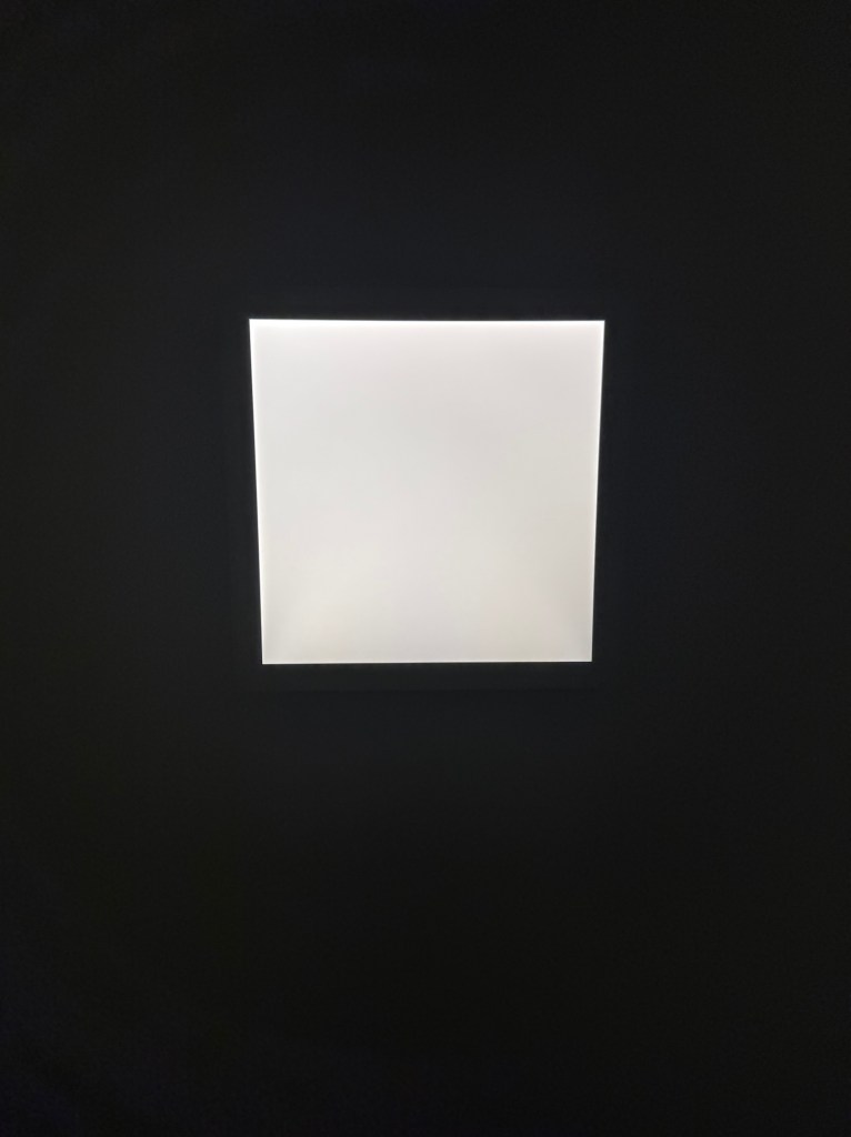 A square light in the center of a dark ceiling