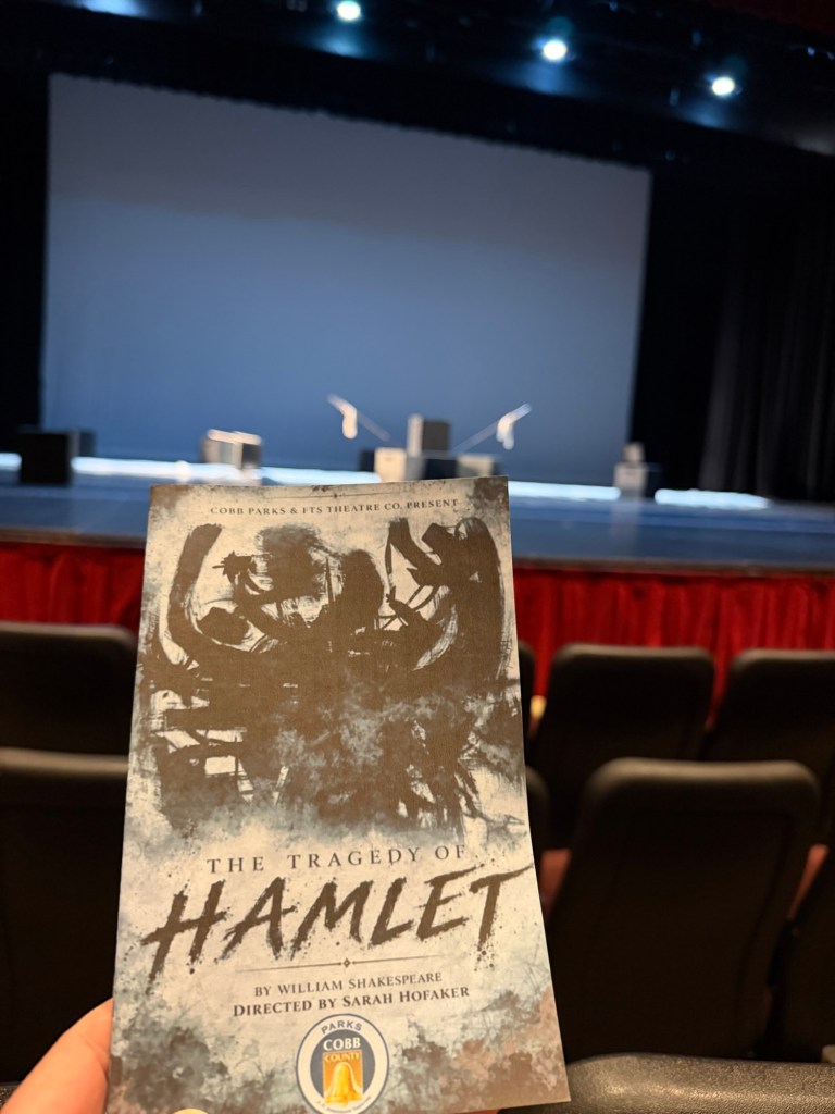 The program for "Hamlet" is in the foreground with the lit empty stage in the background.