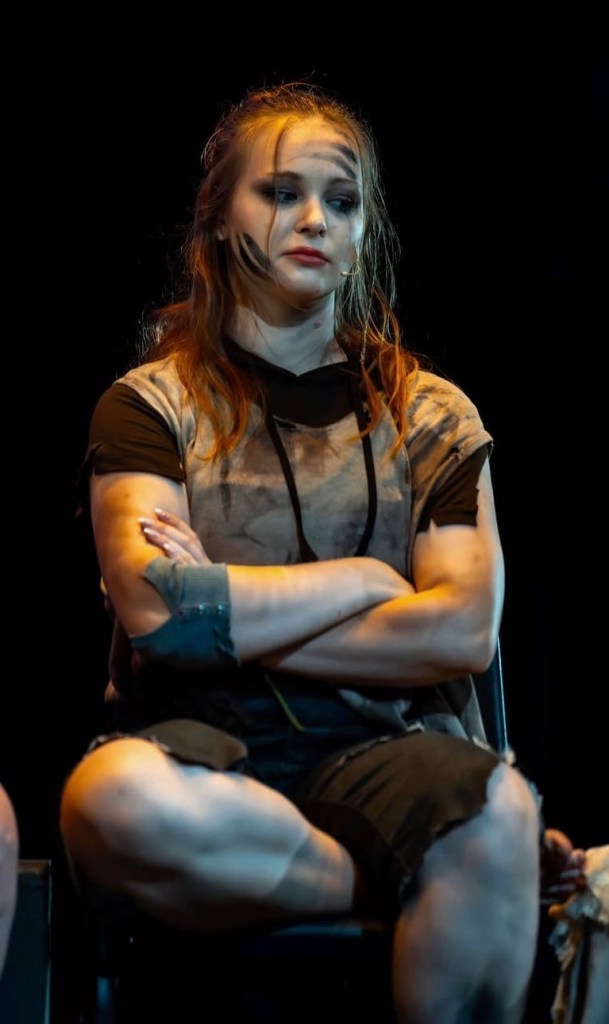 A young woman sits with her arms and legs crossed.