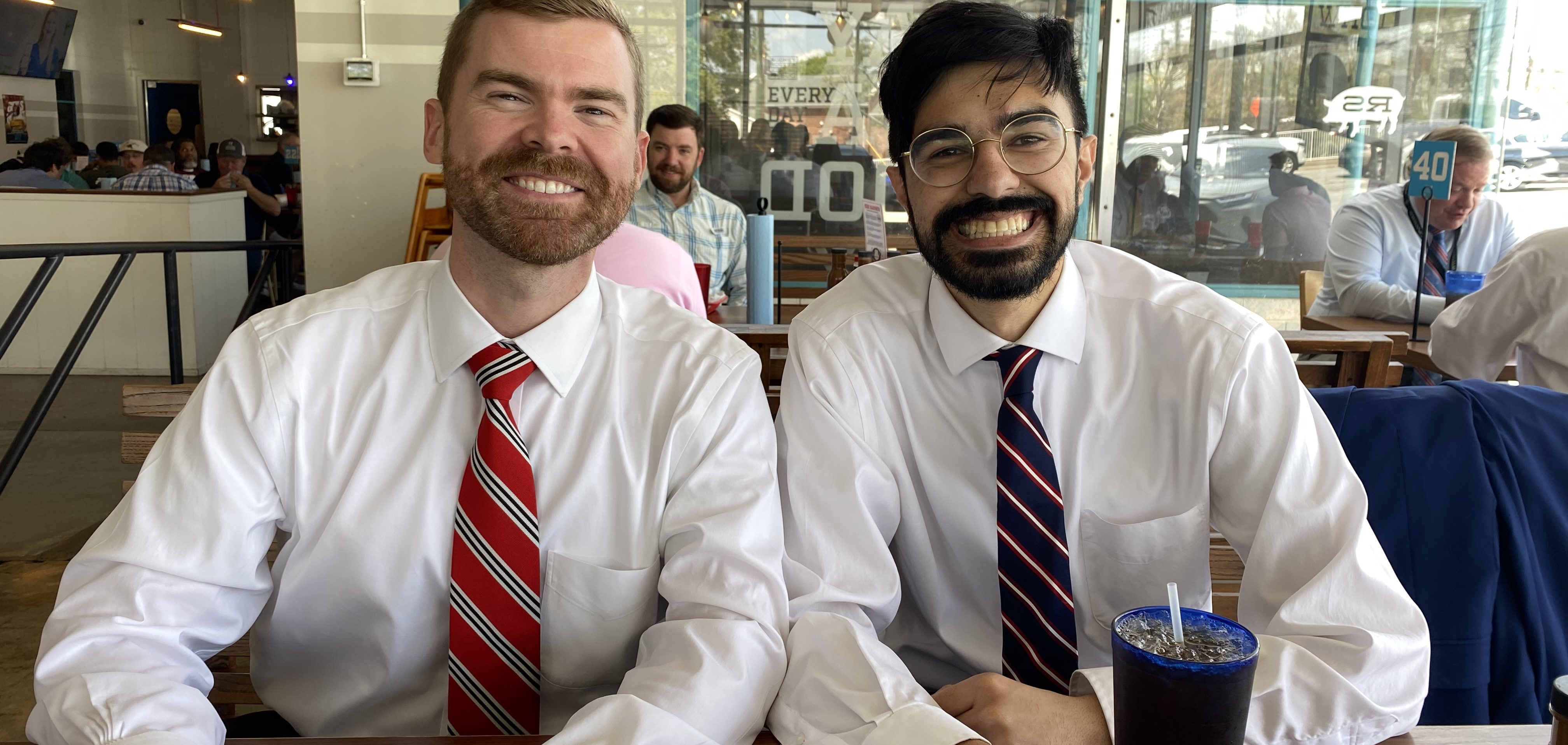 Two men in shirts and ties at a restaurant table.