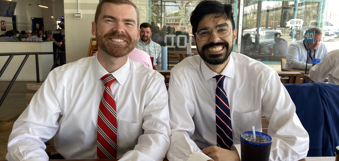 Two men in shirts and ties at a restaurant table.