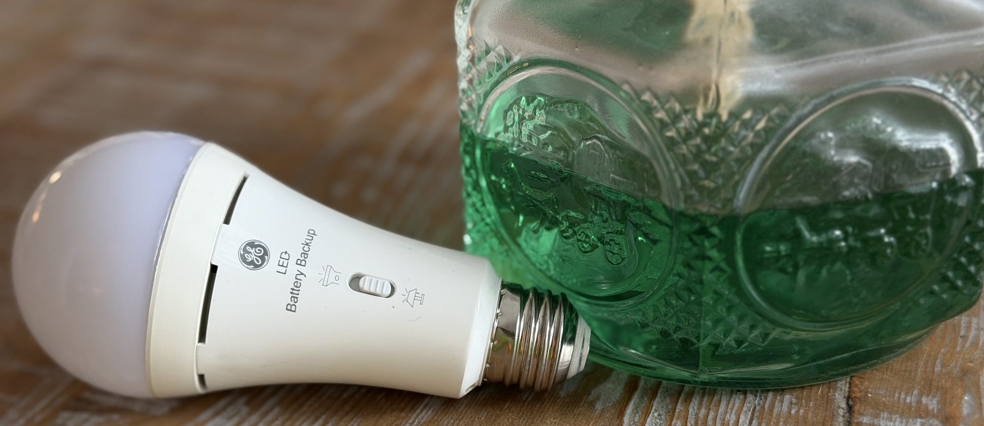 A GE LED battery-powered light bulb and a hurricane lamp filled with green fuel.